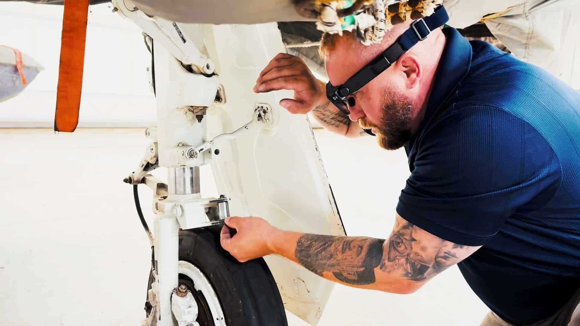 Technician wearing smartglasses inspecting aircraft landing gear while capturing evidence